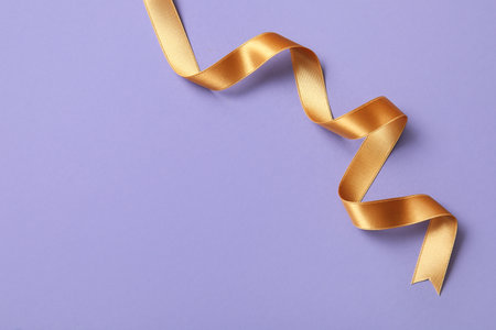 Golden satin ribbon on purple backgroundの写真素材