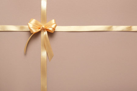Bow made of golden satin ribbons on brown backgroundの写真素材