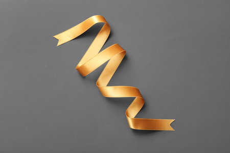 Golden satin ribbon on gray backgroundの写真素材