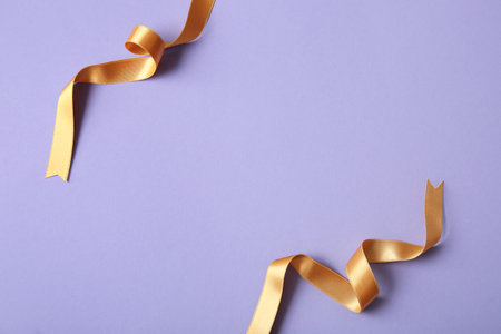 Golden satin ribbons on purple backgroundの写真素材
