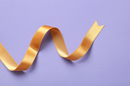 Golden satin ribbon on purple backgroundの写真素材