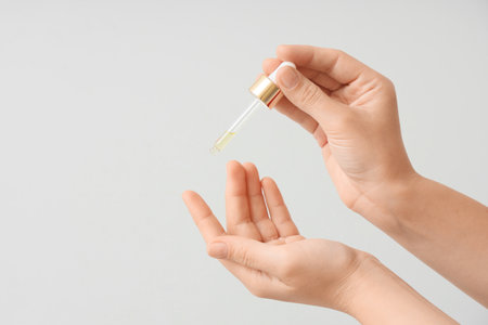 Female hands with essential oil on white backgroundの写真素材