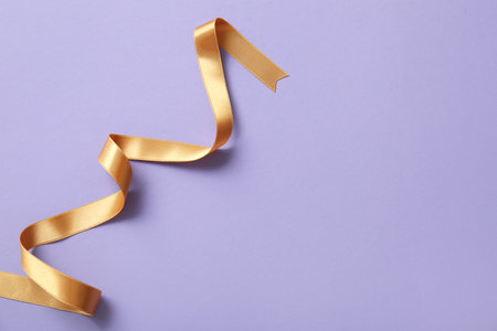 Golden satin ribbon on purple backgroundの写真素材