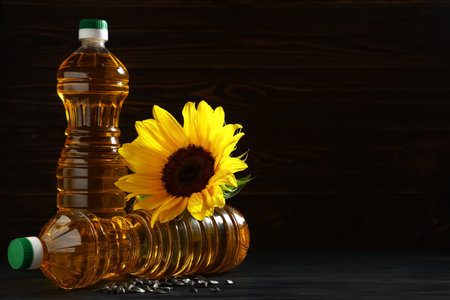 Bottles of oil with sunflower and seeds on dark wooden backgroundの写真素材