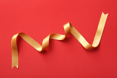 Golden satin ribbon on red backgroundの写真素材
