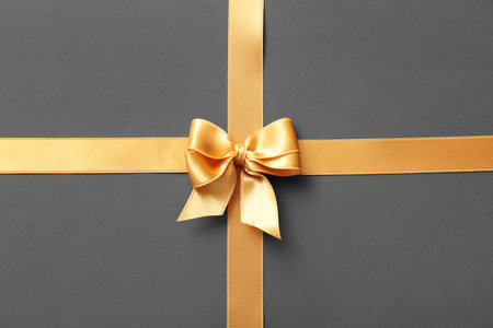 Bow made of golden satin ribbons on gray backgroundの写真素材