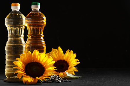 Bottles of oil with sunflowers and seeds on black backgroundの写真素材