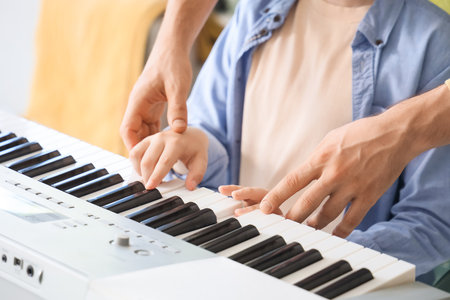 Private music teacher giving synthesizer lessons to boy at home, closeupの写真素材