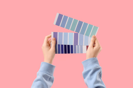 Female hands with color palettes on pink backgroundの写真素材