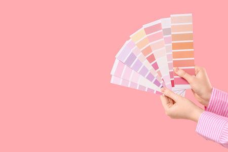 Female hands with color palettes on pink backgroundの写真素材