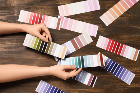 Female hands with many color palettes on brown wooden backgroundの写真素材