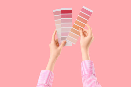 Female hands with color palettes on pink backgroundの写真素材