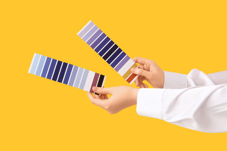 Female hands with color palettes on yellow background