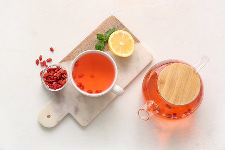 Cup and teapot of hot goji tea with lemon on white backgroundの写真素材