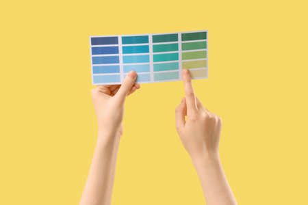 Woman pointing at color palette on yellow backgroundの写真素材