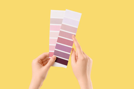 Woman pointing at color palettes on yellow backgroundの写真素材