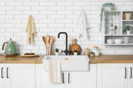Interior of stylish kitchen with white counters, utensils and sink