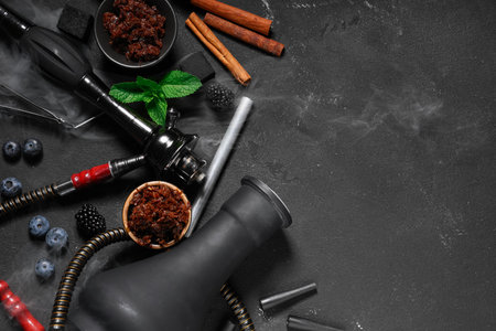 Parts of hookah with tobacco, berries, mint leaves and cinnamon sticks on black backgroundの写真素材