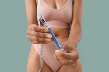 Woman with injection on green background, closeup. Weight loss conceptの写真素材