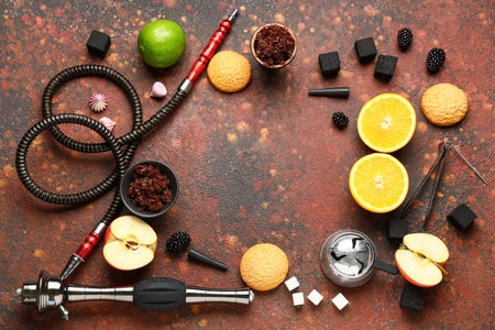 Frame made of hookah parts with tobacco, fruits, berries and cookies on red grunge backgroundの写真素材