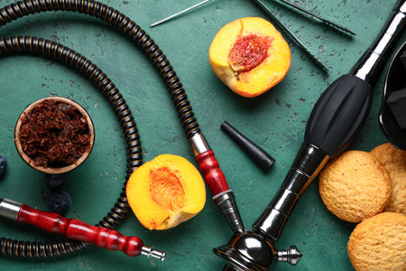 Parts of hookah with tobacco, peach and cookies on green grunge background