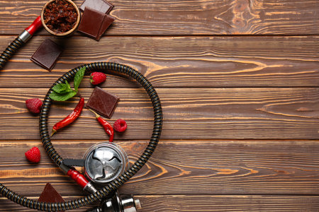 Parts of hookah with tobacco, berries, chocolate pieces, dried chili peppers and mint leaves on...
