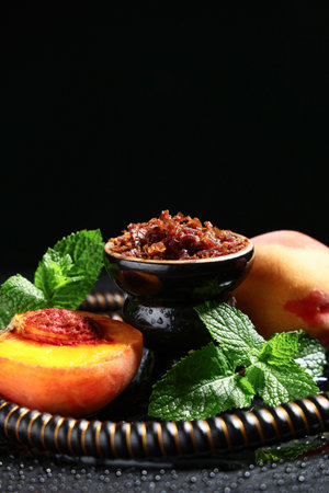 Parts of hookah with tobacco, peaches and mint leaves on black backgroundの写真素材