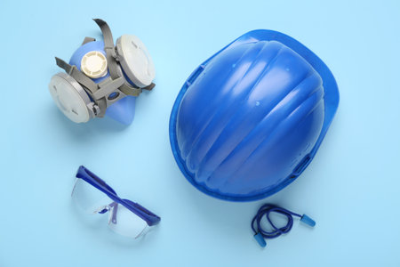 Hardhat with safety goggles, respirator and earplugs on blue backgroundの写真素材