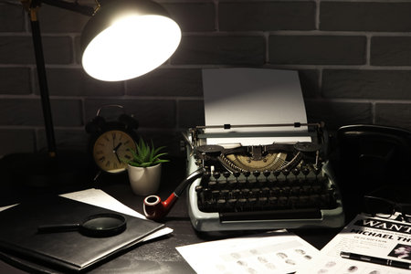 Vintage typewriter with wanted posters and fingerprints on table in dark office