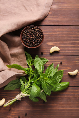 Fresh green basil leaves with garlic and bowl of peppercorns on wooden backgroundの写真素材