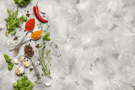Composition with different herbs, spoons and spices on gray grunge backgroundの写真素材
