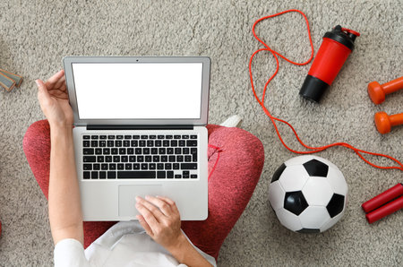 Female blogger using blank laptop with sports equipment on carpet, top viewの写真素材