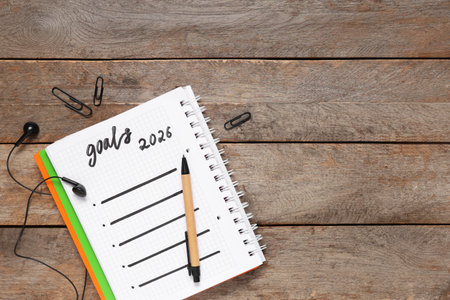 Notebook with 2026 goals and earphones on wooden backgroundの写真素材