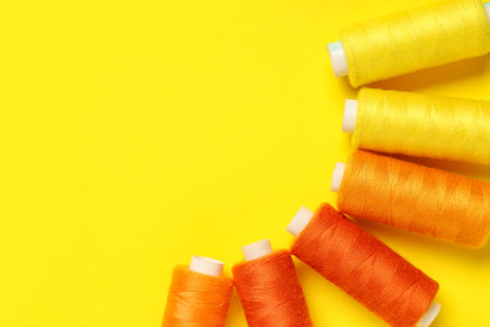 Different thread spools on yellow background