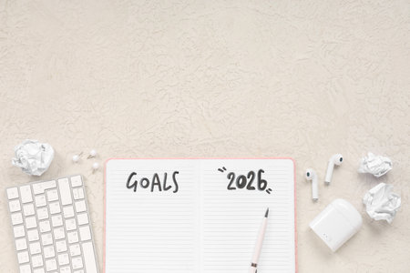 Notebook with 2026 goals, earphones, computer keyboard and crumpled paper on white grunge backgroundの写真素材