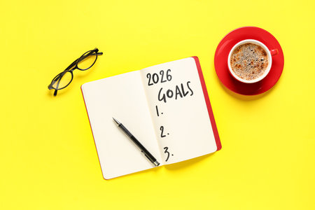 Notebook with empty to do list, eyeglasses and cup of coffee on yellow background. New year goalsの写真素材