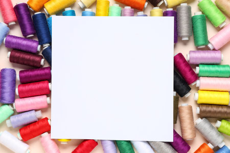 Many different thread spools with blank card on beige background