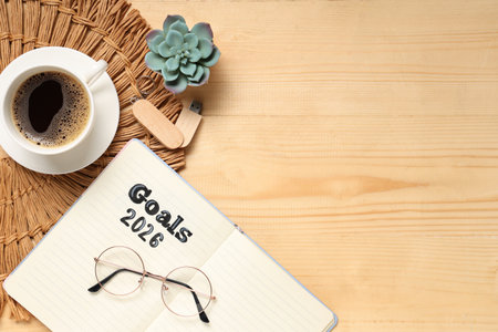 Notebook with 2026 goals, USB flash drive, eyeglasses and coffee on wooden backgroundの写真素材