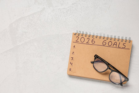 Notebook with 2026 goals and eyeglasses on grunge backgroundの写真素材