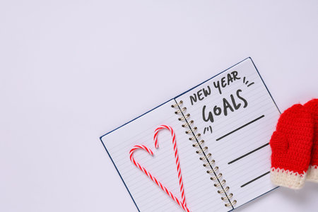 Notebook with new year goals and Christmas decor on white background