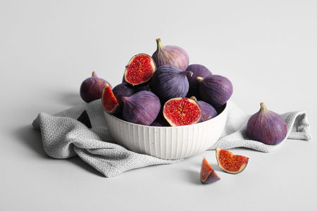 Bowl with fresh ripe figs on gray background