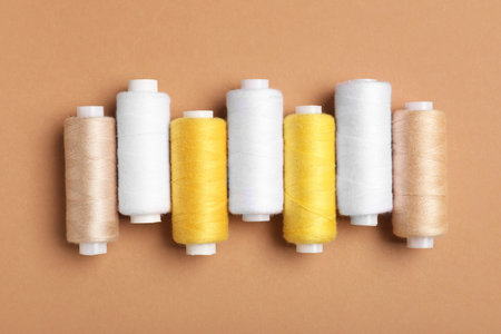 Set of different thread spools on brown background, closeup