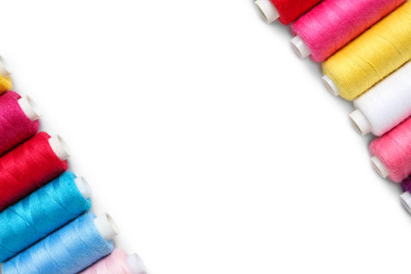 Frame made of colorful thread spools on white background