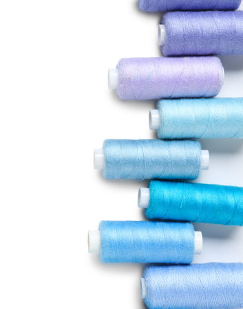 Row of colorful thread spools on white background