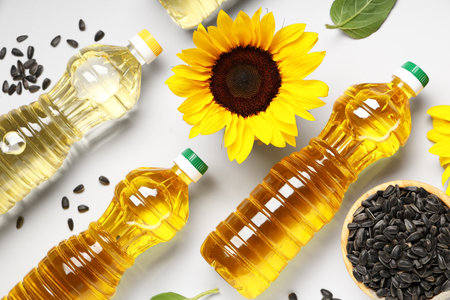 Bottles of oil, sunflower and bowl with seeds on white backgroundの写真素材