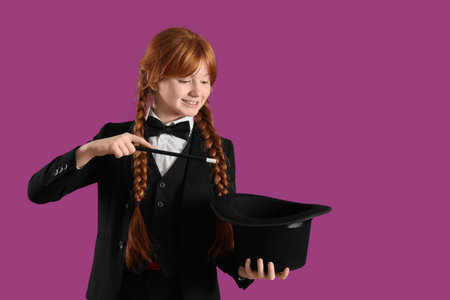 Young magician showing magic trick with hat on purple background