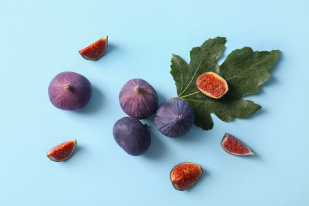 Fresh ripe figs and leaves on blue background