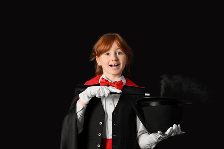 Young magician showing magic trick with hat on black backgroundの写真素材