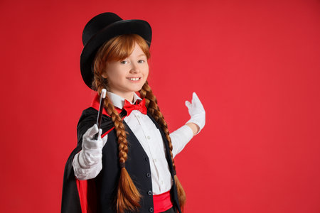 Young magician with magic wand on red backgroundの写真素材