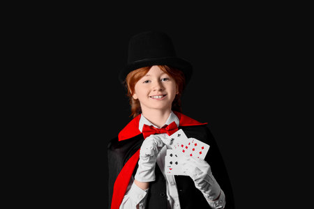 Young magician showing magic trick with playing cards on black backgroundの写真素材